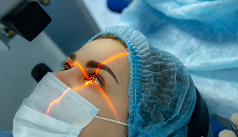 Person mit OP-Maske erhält Laser-Augenoperation; orange Laserstrahlen zielen aufs Auge, medizinische Geräte im Hintergrund.