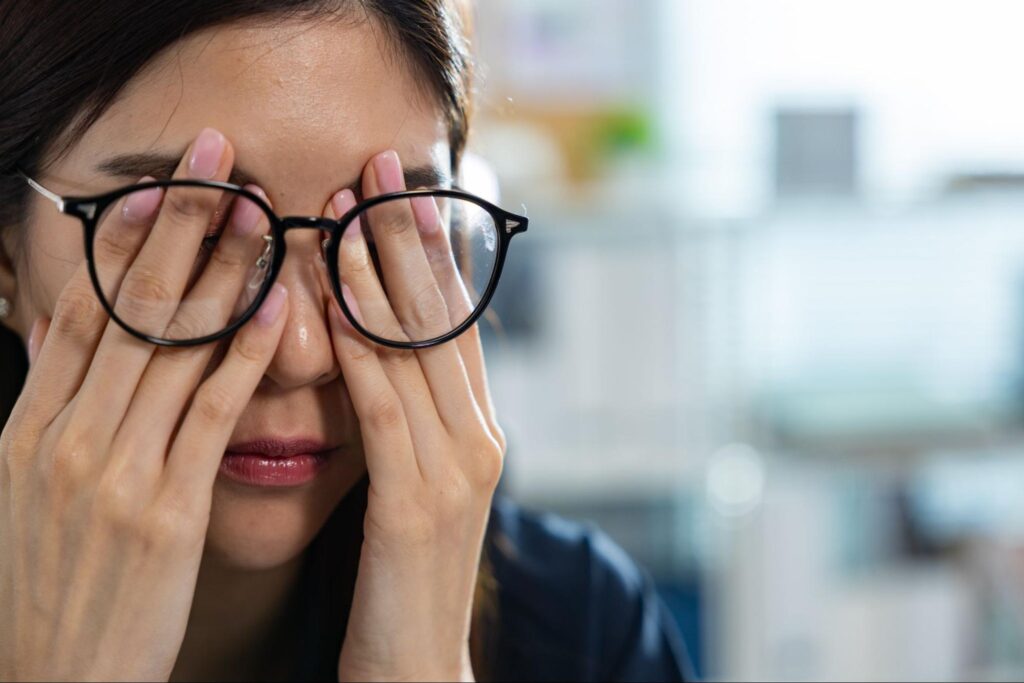 Frau fasst sich an Augen als Symbol für Sehstörungen durch Stress